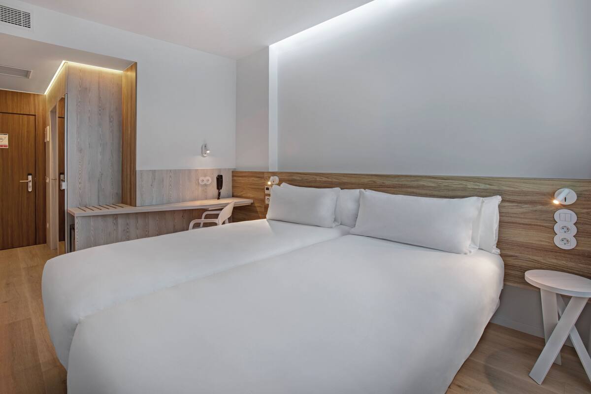 A modern hotel room with a large bed, a desk, and a small table.