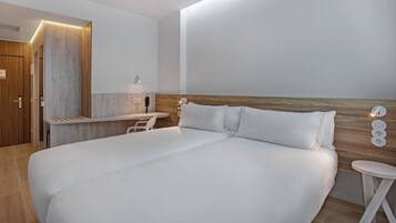 Una habitación de hotel moderna con una cama grande, un escritorio y una pequeña mesa.