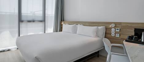 Habitación de hotel moderna con una cama grande, un escritorio y vistas a la ciudad.