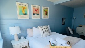Une chambre à coucher comprenant un lit, une table de chevet, une lampe et un mur orné de trois affiches encadrées.