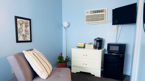 Une pièce comprenant un canapé, une commode blanche, un téléviseur à écran plat, un four à micro-ondes et un ventilateur de plafond.