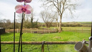 A view from a window overlooking a grassy field with trees and a wooden fence. - Penlon Annex, Aberporth (Aberporth)