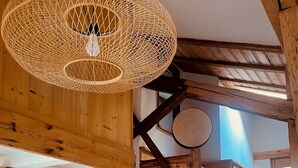 Un interior rústico con vigas de madera a la vista, una escalera de madera y una zona de cocina con electrodomésticos modernos.