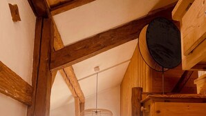 Un interior de madera con techo alto, una lámpara colgante y vista a un espacio exterior a través de un ventanal.
