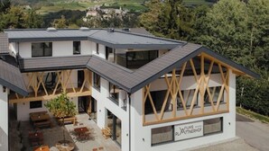 Ein modernes Gebäude mit flachem Dach, großen Fenstern und Holzbalken.