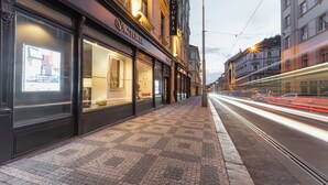 A street view with a storefront labeled "Victoria" and a tram passing by. - EA Hotel Victoria (Prague)