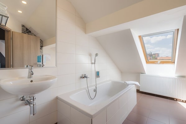 A modern bathroom with a freestanding bathtub, two sinks, and a skylight. - EA Hotel Victoria (Prague)