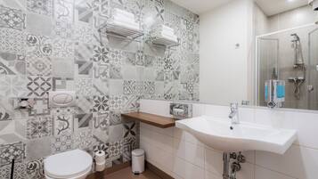 A bathroom with patterned tiles, a toilet, a sink, and a shower.
