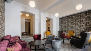 A modern lounge area with plush seating, a patterned wall, and a ceiling with round lights. - EA Hotel Victoria (Prague)