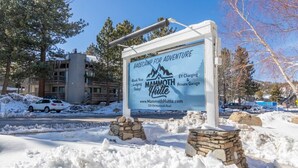 A sign for Mammoth Hutte with a mountain graphic, indicating it's a base camp for adventure. - Downtown Mammoth | Walk to Shops & Eats! MH#5 (Mammoth Lakes)