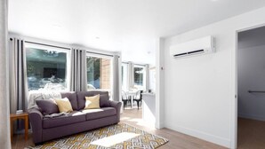 A modern living room with a sofa, a patterned rug, and a dining area visible through large windows. - Downtown Mammoth | Walk to Shops & Eats! MH#5 (Mammoth Lakes)