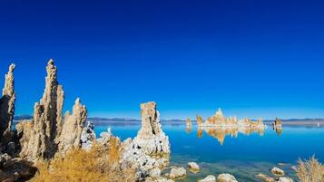 Un lac aux eaux limpides, bordé de formations rocheuses, et un ciel d’un bleu éclatant.