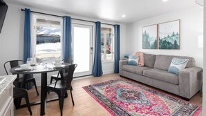 A dining area with a table set for four, a sofa, and a large rug. - New! Near Restaurants and Shopping #6 (Mammoth Lakes)
