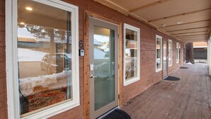 A covered wooden building with large windows, a door with a number, and a wooden deck. - New! Near Restaurants and Shopping #6 (Mammoth Lakes)