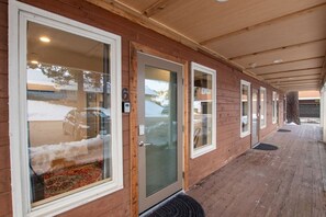 Un edificio in legno con tetto, ampie finestre, una porta con un numero e un’uscita su un patio in legno.