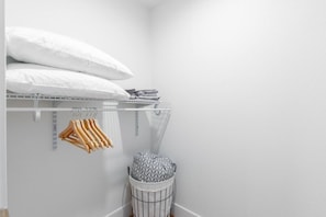 Un placard blanc avec des étagères, une tringle et un panier.