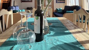 A dining area with a wooden ceiling, a table set with wine glasses and a bottle, and a tropical bird on the table. - Villa Finca Tijarafe with heated pool (Tijarafe)