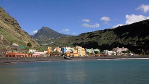 A coastal town with buildings along the shore, a mountain in the background, and a clear sky. - Villa Finca Tijarafe with heated pool (Tijarafe)