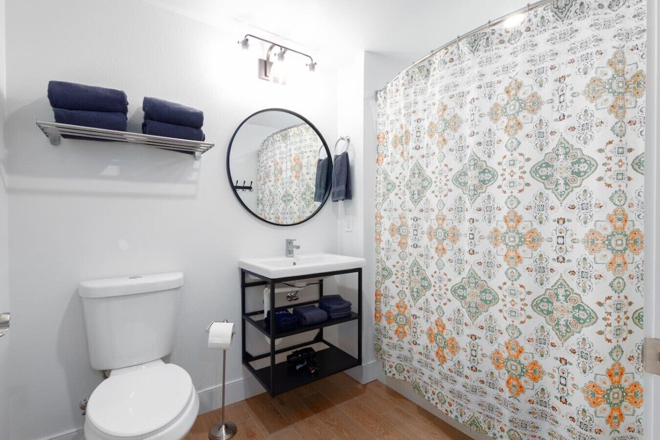 A bathroom with a toilet, sink, mirror, towel rack, and shower curtain.