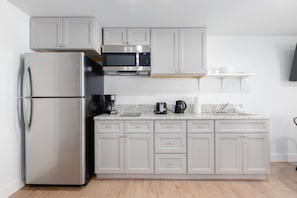 A modern kitchen with a refrigerator, microwave, coffee maker, and toaster.