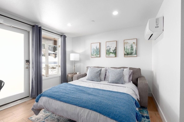 A bedroom with a bed, a nightstand, a lamp, and a window with curtains.