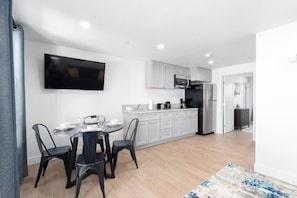 A modern kitchen with white cabinets, a black refrigerator, and a microwave.
