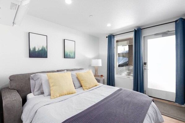 A bedroom with a bed, a nightstand, a lamp, and a window with curtains.
