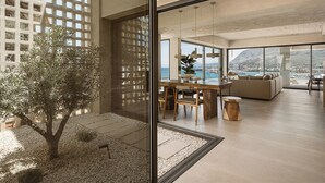A modern interior with a dining area, seating, and a view of the sea. - Villa Albero: Your Stay, a Seaview Journey (Souda)