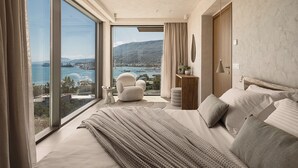 A bedroom with a large bed, a view of the sea, and a cityscape. - Villa Albero: Your Stay, a Seaview Journey (Souda)