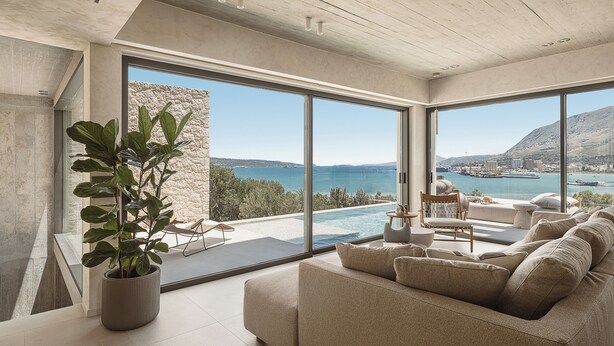 A modern living room with a large sofa, a coffee table, and a potted plant. - Villa Albero: Your Stay, a Seaview Journey (Souda)
