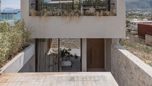 A modern two-story building with a balcony overlooking a scenic landscape. - Villa Albero: Your Stay, a Seaview Journey (Souda)