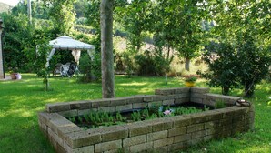 A garden with a raised brick planter, a small pond, and a gazebo. - Casa il Girasole con piscina  (Macerata)