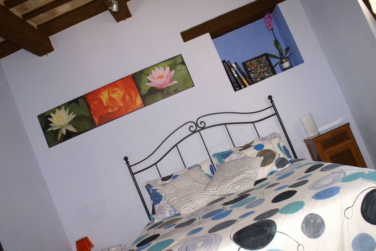 Une chambre à coucher avec un lit, un tableau accroché au mur et une table de chevet.