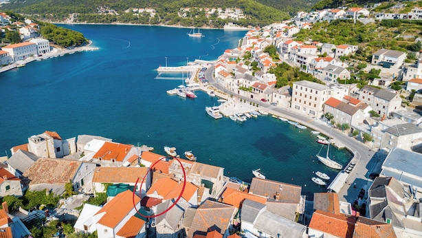 Un pueblo costero con edificios históricos, un puerto deportivo y barcos.