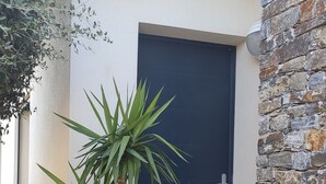 A modern building with a stone wall and a dark door. - Studio à Mora Dell Onda 20137 Lecci (LECCI)