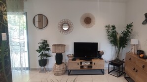 A living room with a flat-screen TV, wooden cabinets, a potted plant, and decorative wall art. - Studio à Mora Dell Onda 20137 Lecci (LECCI)