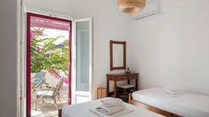 Ein Schlafzimmer mit zwei Betten, einem Holznachttisch, einem Spiegel und einer Weidenpendelleuchte.