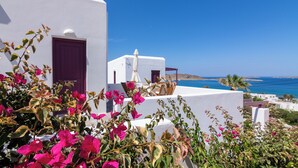 Ein weißes Gebäude mit einer violetten Tür, einem Tisch mit Stühlen und Blick auf das Meer.