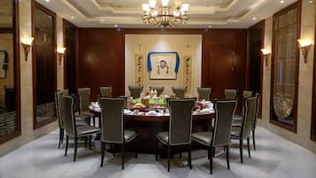 A formal dining room with a round table, eight chairs, and a chandelier.