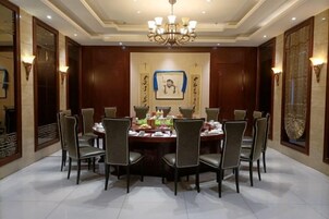 A formal dining room with a round table, eight chairs, and a chandelier.