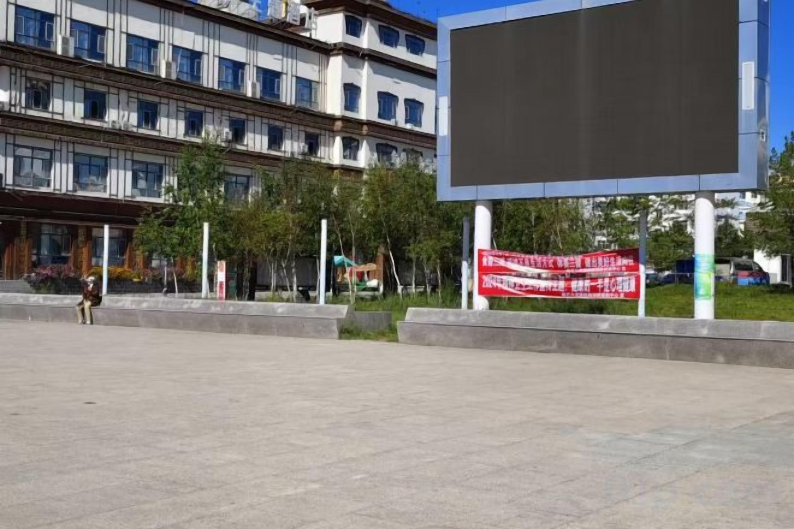 A building with multiple floors and a large blank billboard in front.