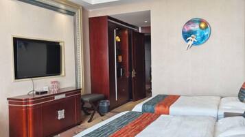 A hotel room with a bed, a TV, a wardrobe, and a painting of a planet.