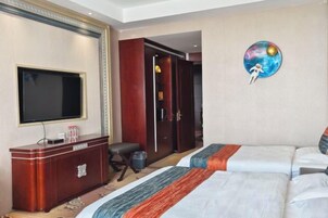 Habitación de hotel con cama, televisor, armario y un cuadro de un planeta.