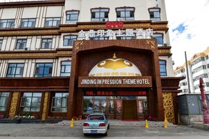Entrada de hotel con un cartel llamativo que dice "JINDING IMPRESSION THEME HOTEL".