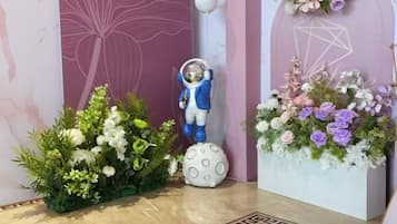 A room with a large floral arrangement, a statue of a figure in a space suit, and a geometric wall design.