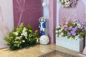 A room with a large floral arrangement, a statue of a figure in a space suit, and a geometric wall design. - Jinding Impression Theme Hotel, Chenbar Tiger Banner (Old Barag Banner)