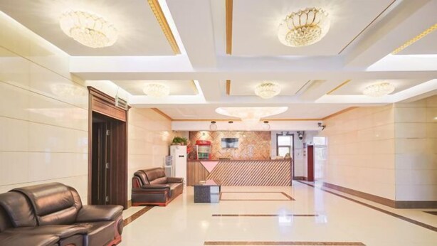 A hotel lobby with a reception desk, leather sofas, and a patterned wall. - Home Inn Huayi Hotel (Xinmin Liaohe Street) (Xinmin)