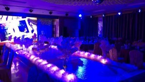 A room with a long table, chairs, and a stage with a large screen. - Home Inn Huayi Hotel (Xinmin Liaohe Street) (Xinmin)