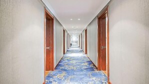 A long, narrow hallway with wooden doors on both sides and a blue carpet with floral patterns. - Home Inn Huayi Hotel (Xinmin Liaohe Street) (Xinmin)