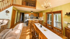 A spacious kitchen with wooden cabinets, a dining area with a long table, and a staircase leading to an upper level.